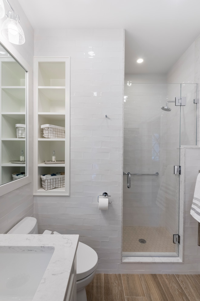 Photo of a mid-sized transitional kids bathroom in Boston with recessed-panel cabinets, grey cabinets, a drop-in tub, a one-piece toilet, white tile, porcelain tile, blue walls, porcelain floors, an undermount sink, engineered quartz benchtops, white floor and a hinged shower door.