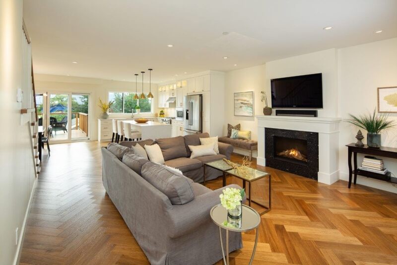 Photo of a mid-sized transitional open concept living room in Vancouver with white walls, a standard fireplace, a metal fireplace surround, a wall-mounted tv, brown floor and vinyl floors.