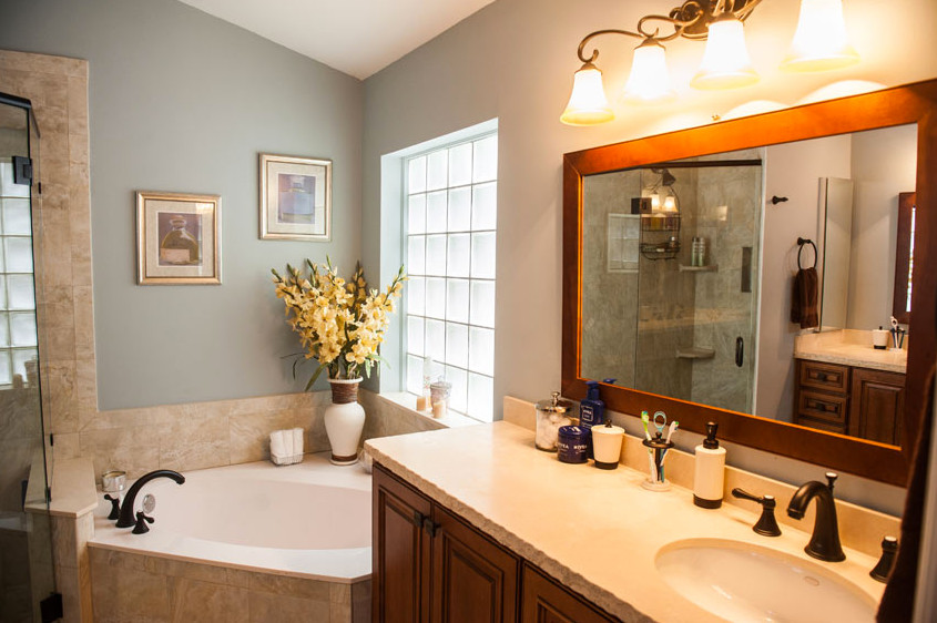 Drop-in bathtub - mid-sized transitional master beige tile and ceramic tile drop-in bathtub idea in Miami with raised-panel cabinets, medium tone wood cabinets, blue walls, an undermount sink and solid surface countertops