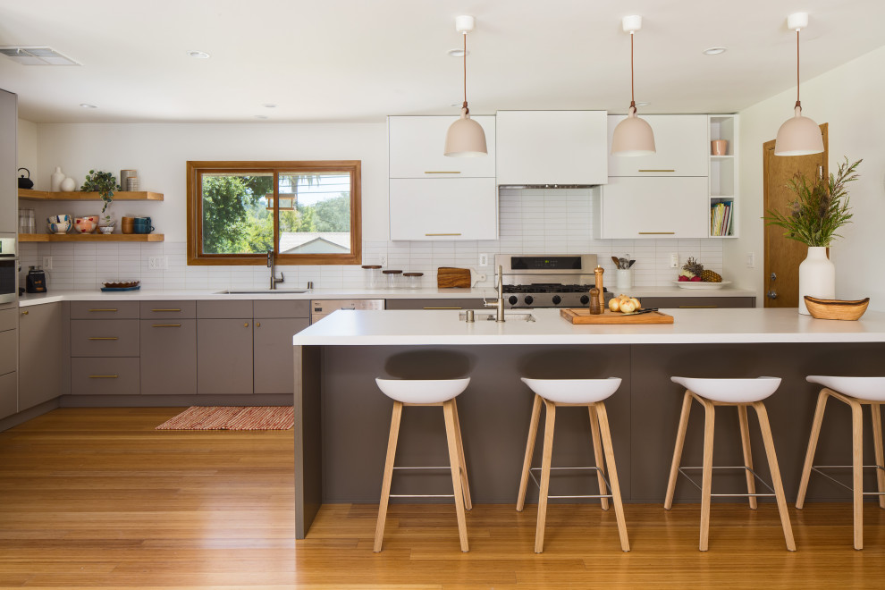 Inspiration for a scandinavian l-shaped kitchen in Los Angeles with an undermount sink, flat-panel cabinets, grey cabinets, quartz benchtops, white splashback, stainless steel appliances, bamboo floors, a peninsula and white benchtop.
