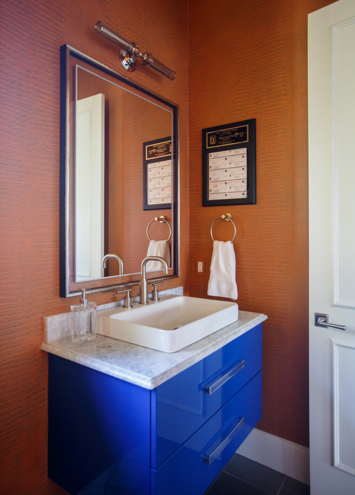 Inspiration for a modern bathroom in Jacksonville with flat-panel cabinets, blue cabinets, a one-piece toilet, orange walls, porcelain floors, a vessel sink, marble benchtops, grey floor and a hinged shower door.