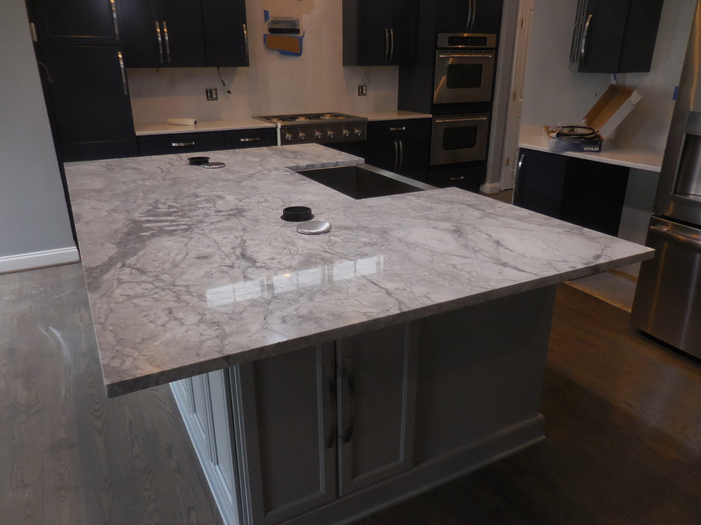 Example of a mid-sized transitional l-shaped medium tone wood floor home design design in Baltimore with a farmhouse sink, recessed-panel cabinets, gray cabinets, quartzite countertops, stainless steel appliances and an island