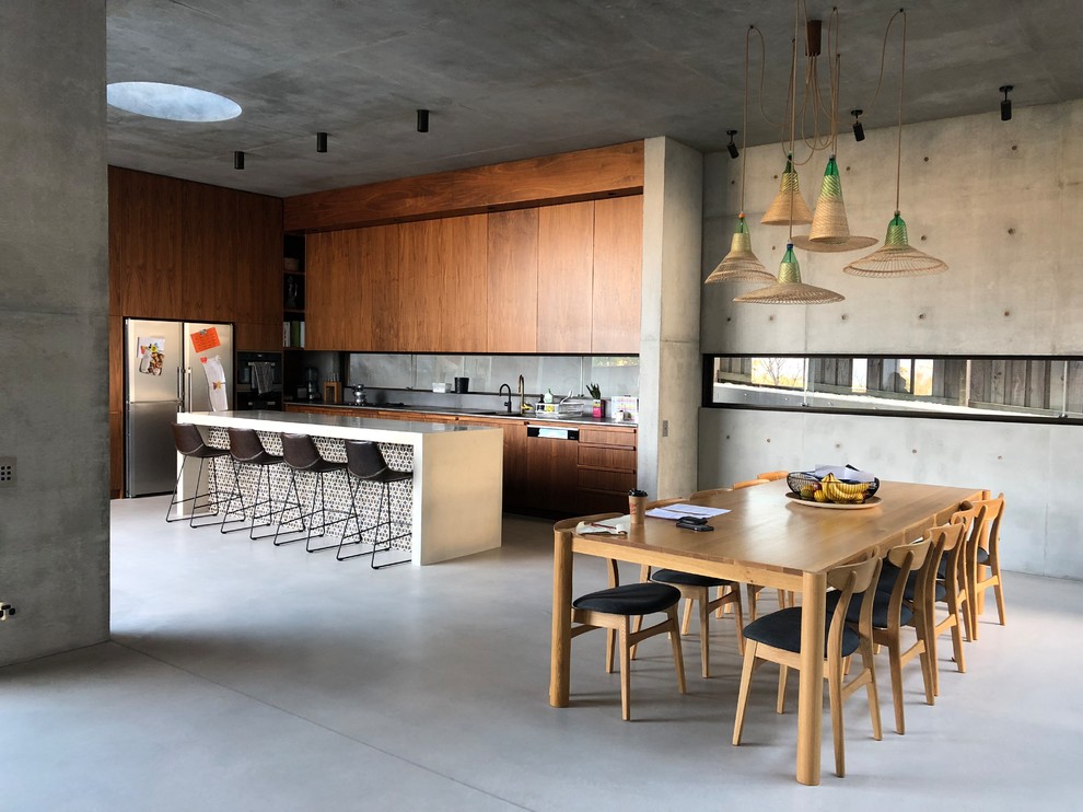 Photo of an industrial l-shaped kitchen in Sydney with flat-panel cabinets, dark wood cabinets, stainless steel appliances, concrete floors, with island, grey floor and white benchtop.