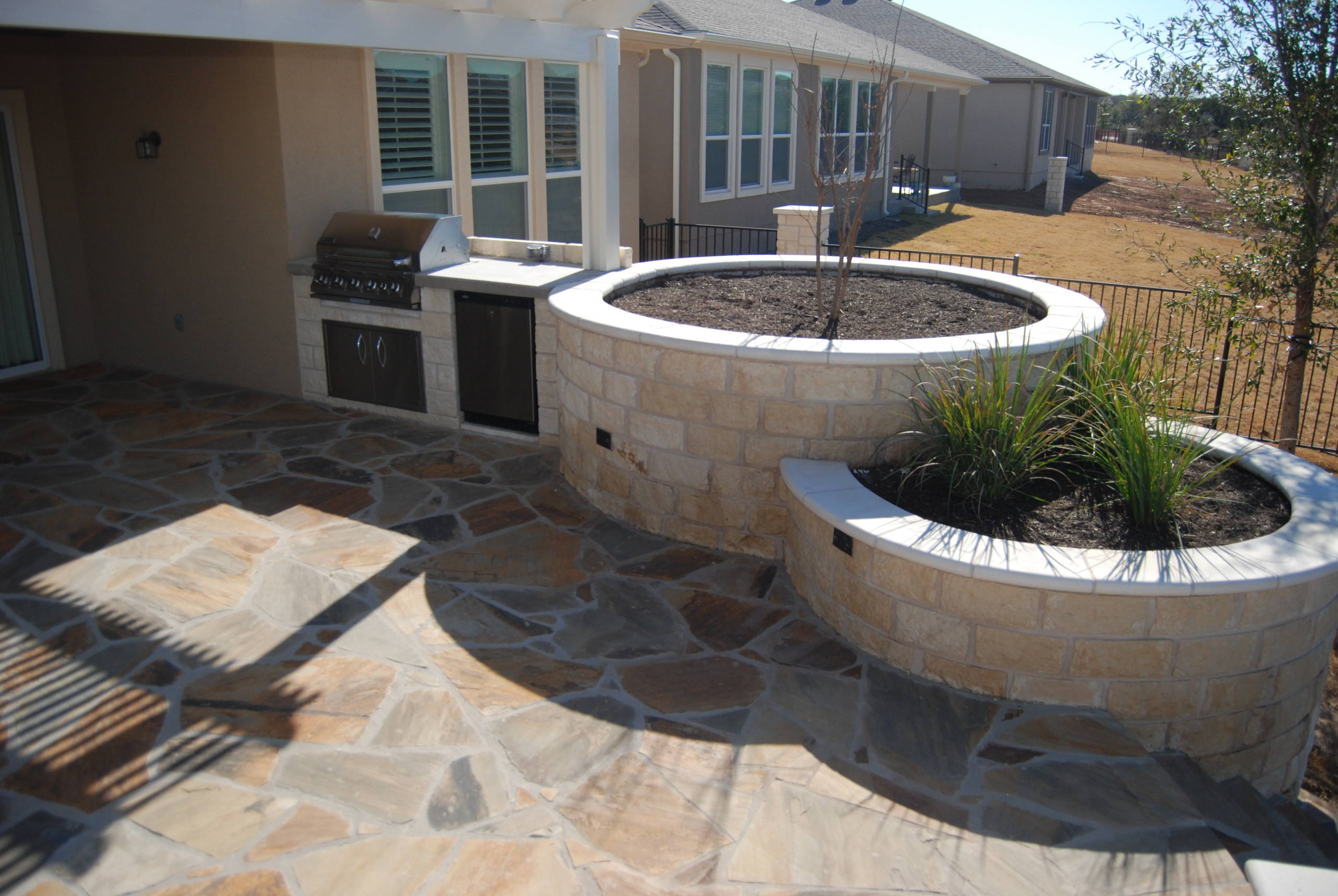 Oklahoma flagstone patio, "round" limestone raised beds with small outdoor kitch
