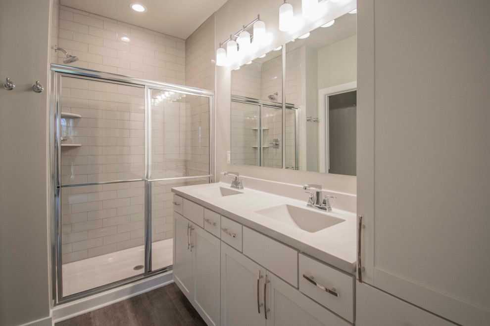 Idéer för att renovera ett stort vit vitt en-suite badrum, med luckor med infälld panel, vita skåp, en dusch i en alkov, en toalettstol med hel cisternkåpa, grå kakel, tunnelbanekakel, grå väggar, vinylgolv, ett integrerad handfat, marmorbänkskiva, brunt golv och dusch med skjutdörr