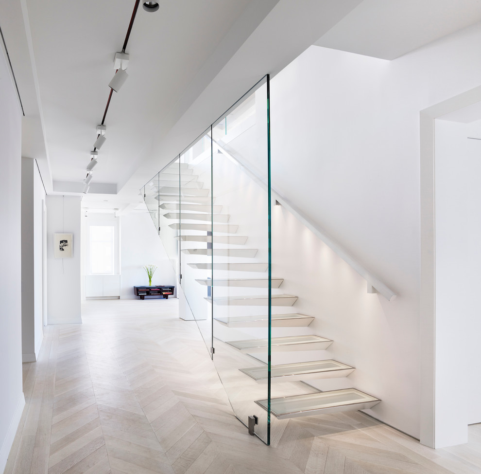 This is an example of a mid-sized contemporary glass floating staircase in New York with open risers and wood railing.