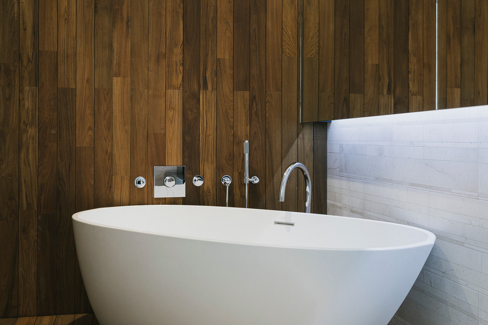 Contemporary master bathroom in New York with a freestanding tub and brown walls.
