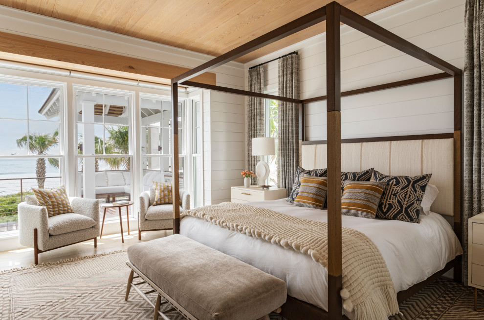 This is an example of an expansive beach style master bedroom in Charleston with white walls, light hardwood floors, beige floor, wood and planked wall panelling.