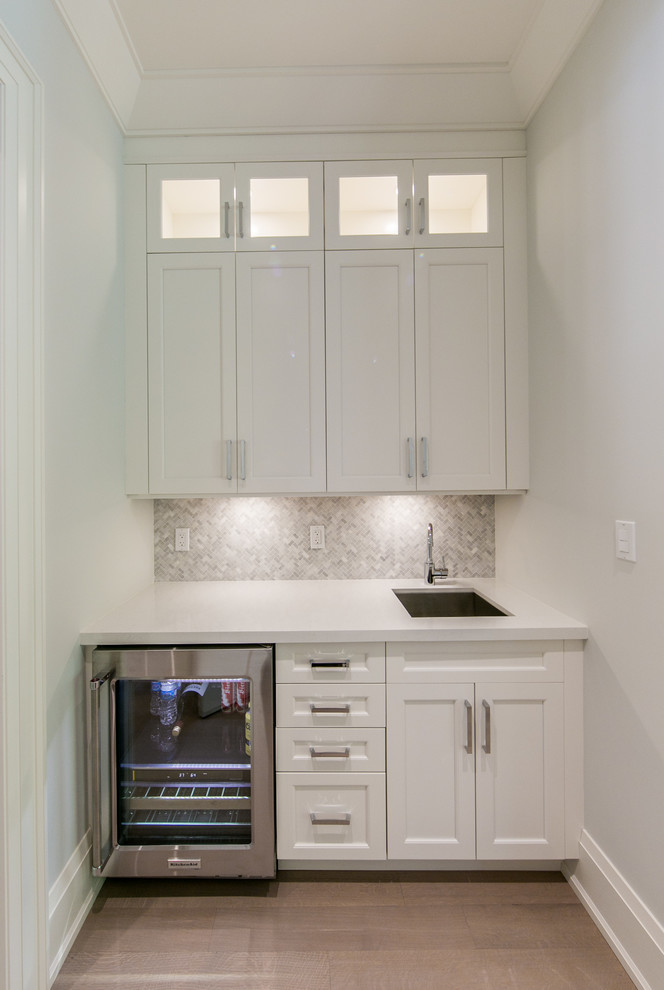 Inspiration for a small transitional single-wall wet bar in Toronto with shaker cabinets, grey splashback, light hardwood floors, an undermount sink, white cabinets, quartzite benchtops and mosaic tile splashback.