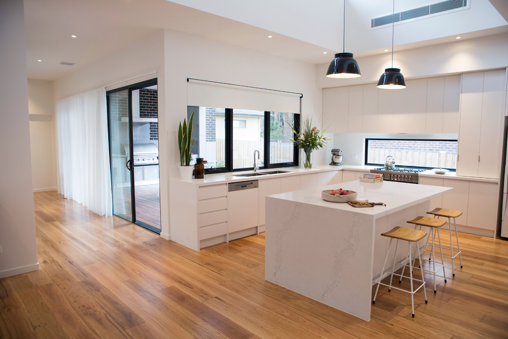 Design ideas for a large contemporary l-shaped eat-in kitchen in Melbourne with white cabinets, quartz benchtops, stainless steel appliances, light hardwood floors, with island, a double-bowl sink, flat-panel cabinets and window splashback.