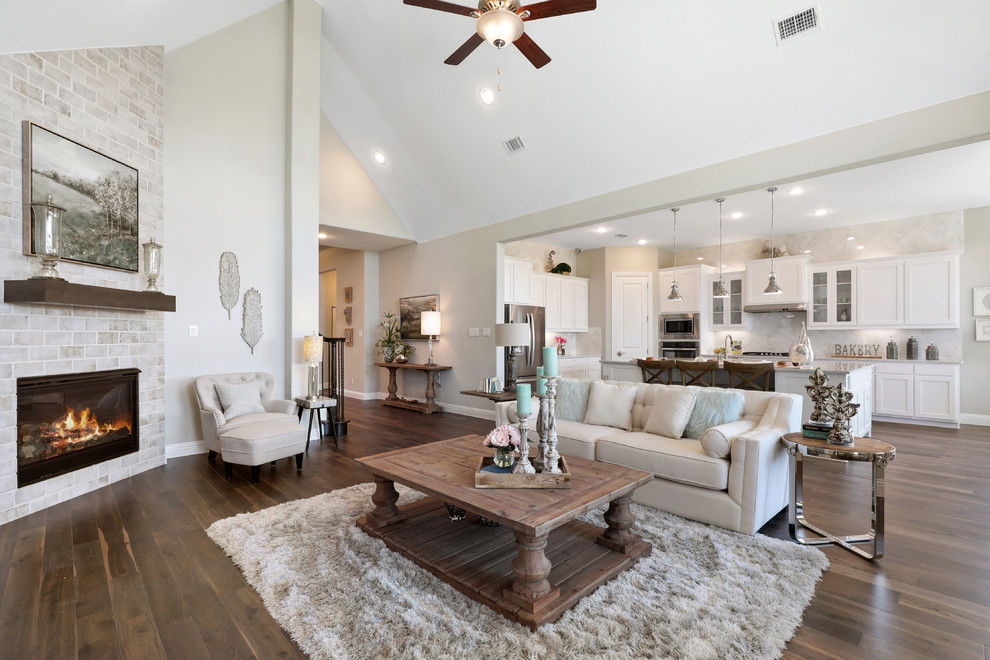This is an example of a mid-sized transitional open concept living room in Dallas with beige walls, a corner fireplace, a brick fireplace surround, brown floor and dark hardwood floors.