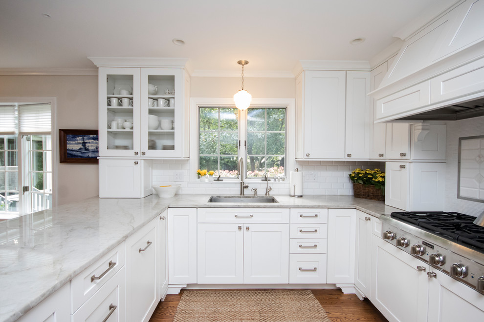 Inspiration for a large traditional l-shaped eat-in kitchen in Providence with an undermount sink, recessed-panel cabinets, white cabinets, granite benchtops, white splashback, ceramic splashback, stainless steel appliances, medium hardwood floors, a peninsula and brown floor.