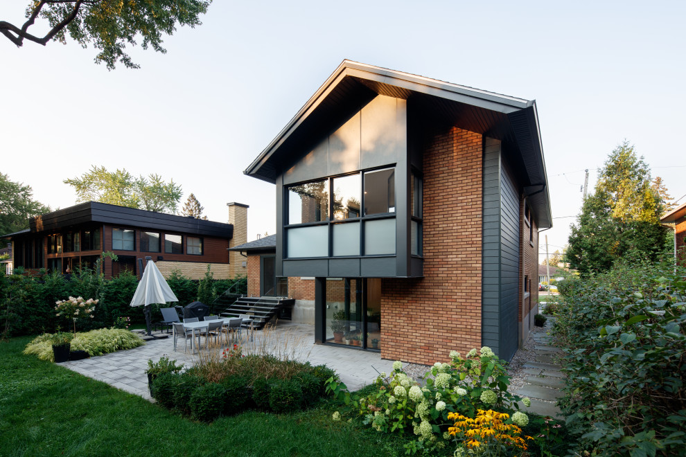 Идея дизайна: маленький, двухэтажный, кирпичный, оранжевый частный загородный дом в стиле ретро с двускатной крышей, крышей из гибкой черепицы, черной крышей и отделкой дранкой для на участке и в саду