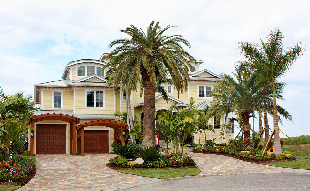Inspiration for an expansive tropical three-storey yellow exterior in Tampa with mixed siding and a hip roof.