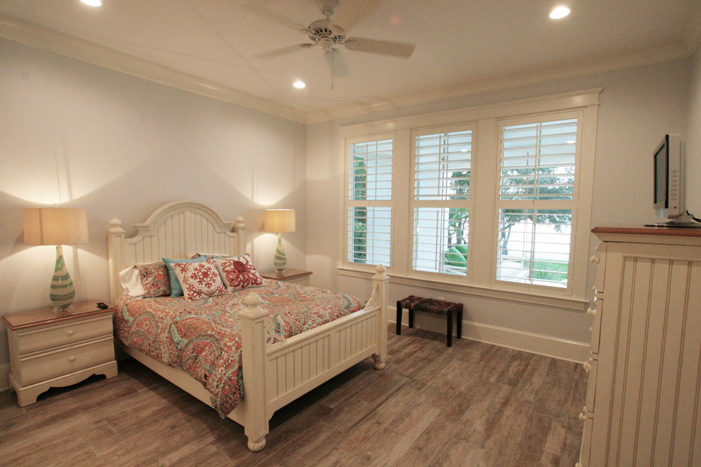 Large beach style guest bedroom with grey walls, dark hardwood floors and no fireplace.