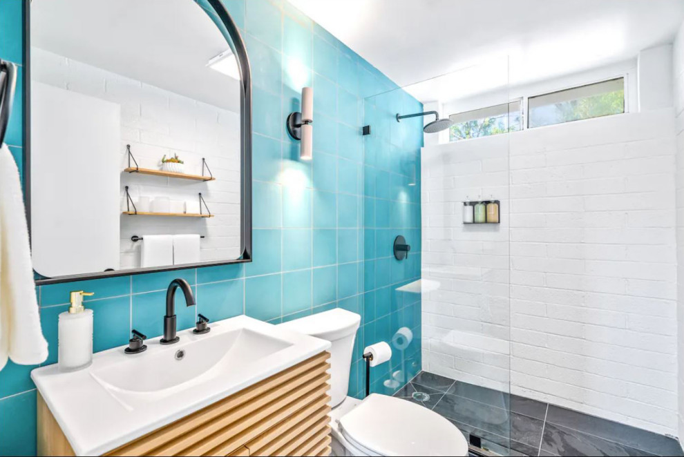 他の地域にあるミッドセンチュリースタイルのおしゃれな浴室 (家具調キャビネット、中間色木目調キャビネット、オープン型シャワー、青いタイル、セメントタイル、白い壁、スレートの床、一体型シンク、クオーツストーンの洗面台、黒い床、オープンシャワー、白い洗面カウンター、洗面台1つ、独立型洗面台、レンガ壁) の写真