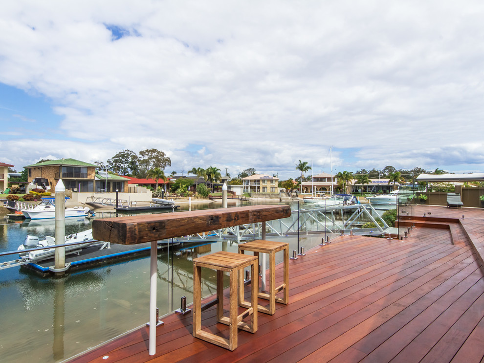 Photo of a large contemporary backyard deck in Brisbane with with dock and a roof extension.