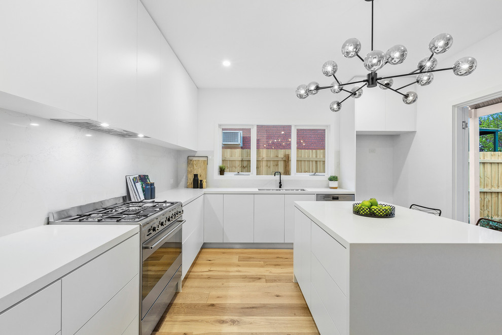 Inspiration for a small contemporary l-shaped eat-in kitchen in Melbourne with an undermount sink, white cabinets, quartz benchtops, white splashback, marble splashback, stainless steel appliances, light hardwood floors, with island and white benchtop.