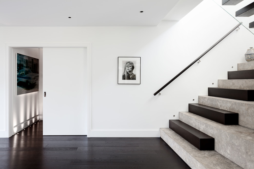 Large contemporary limestone u-shaped staircase in London with wood risers and wood railing.