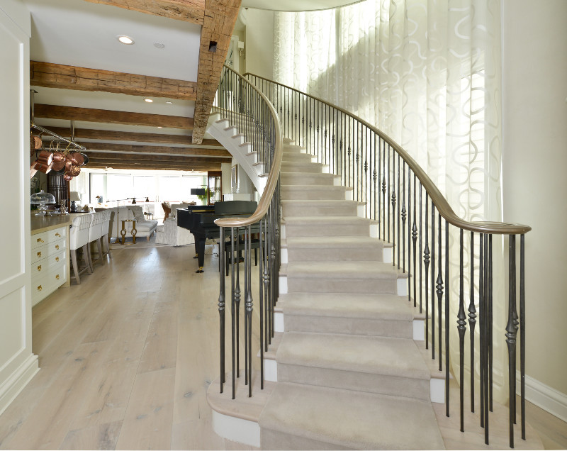 This is an example of a mid-sized transitional wood curved staircase in Baltimore with painted wood risers and metal railing.