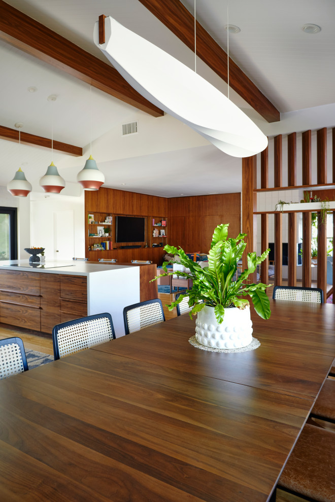 Diseño de comedor retro abierto con paredes blancas, suelo de madera clara y vigas vistas