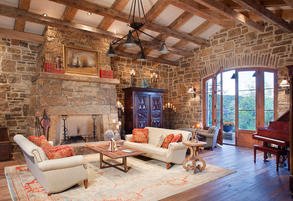 Photo of a large country formal enclosed living room in Denver with dark hardwood floors, beige walls, a standard fireplace, a stone fireplace surround, a concealed tv, multi-coloured floor and exposed beam.