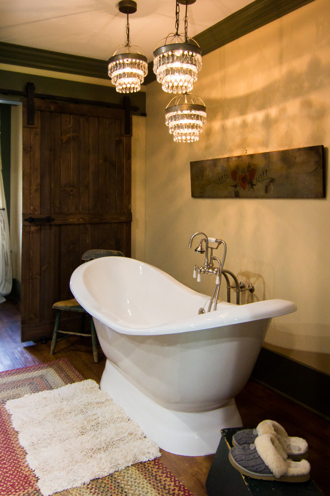 Inspiration for a large rustic master medium tone wood floor freestanding bathtub remodel with furniture-like cabinets, beige cabinets, a two-piece toilet, beige walls, an undermount sink, solid surface countertops and a hinged shower door