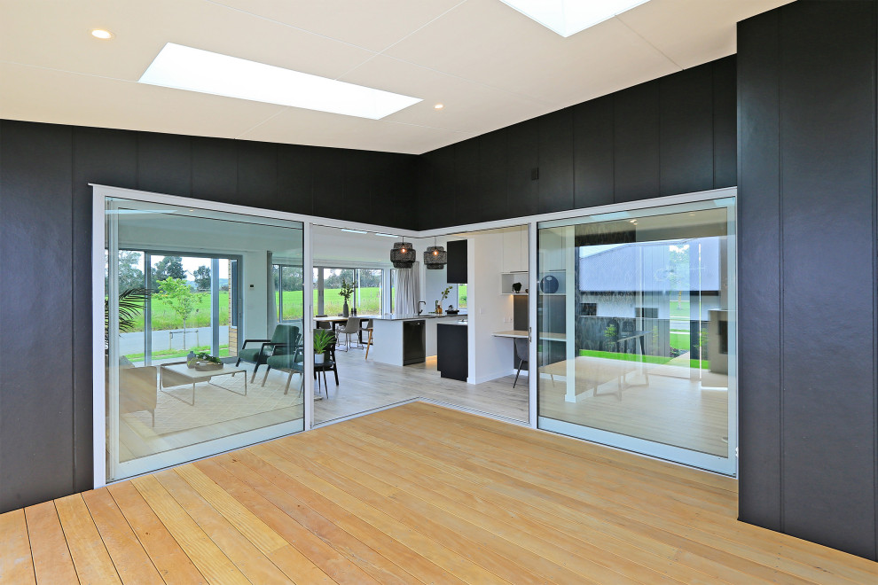 Diseño de galería moderna de tamaño medio con suelo de madera clara, todas las chimeneas, marco de chimenea de hormigón, techo con claraboya y suelo marrón