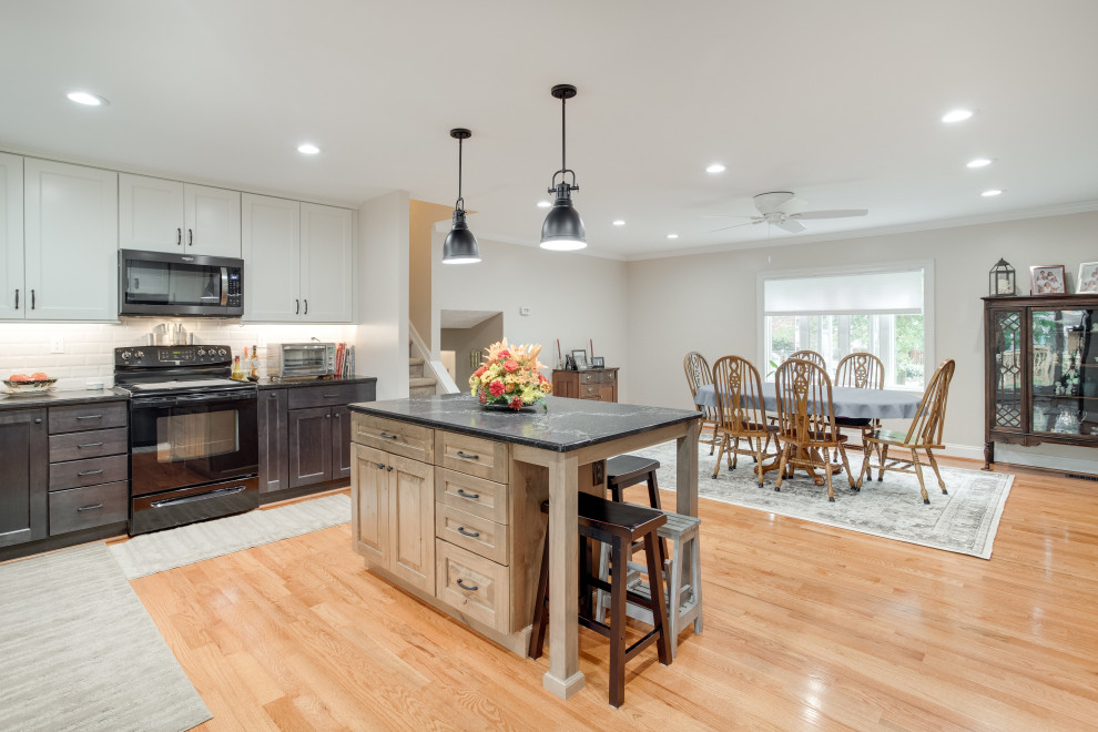 Inspiration for a large transitional u-shaped kitchen remodel in Baltimore with recessed-panel cabinets, quartz countertops, black appliances and an island