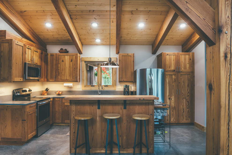 Inspiration for a large rustic l-shaped concrete floor and gray floor enclosed kitchen remodel with shaker cabinets, medium tone wood cabinets, stainless steel appliances and an island