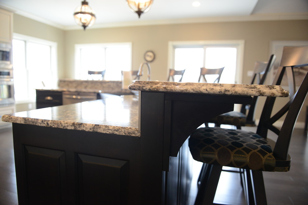 Eat-in kitchen - huge transitional l-shaped medium tone wood floor eat-in kitchen idea in Chicago with a farmhouse sink, raised-panel cabinets, white cabinets, granite countertops, beige backsplash, stone tile backsplash, stainless steel appliances and an island