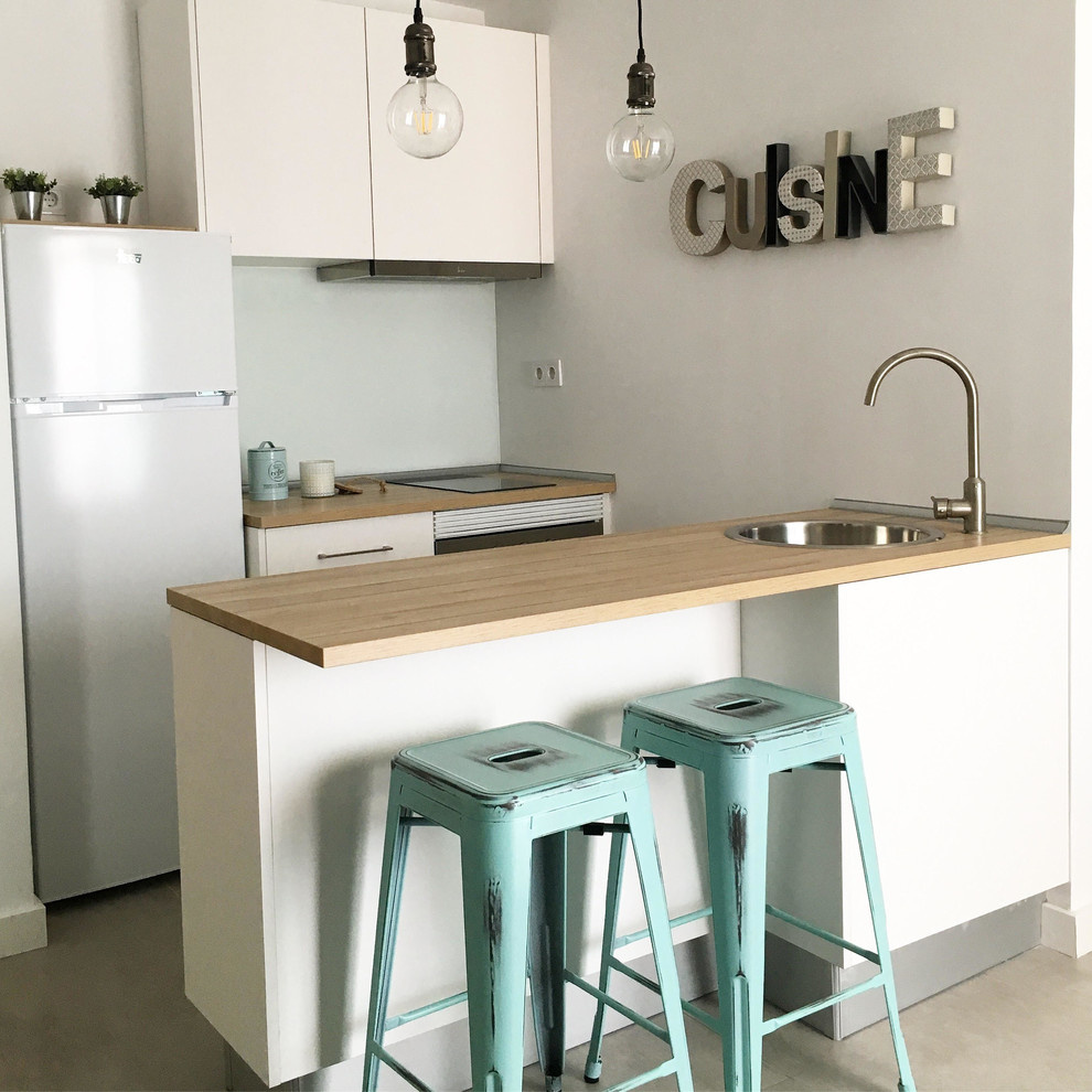 This is an example of a small scandinavian single-wall open plan kitchen in Malaga with a drop-in sink, flat-panel cabinets, white cabinets, laminate benchtops, green splashback, window splashback, white appliances, porcelain floors, a peninsula and grey floor.