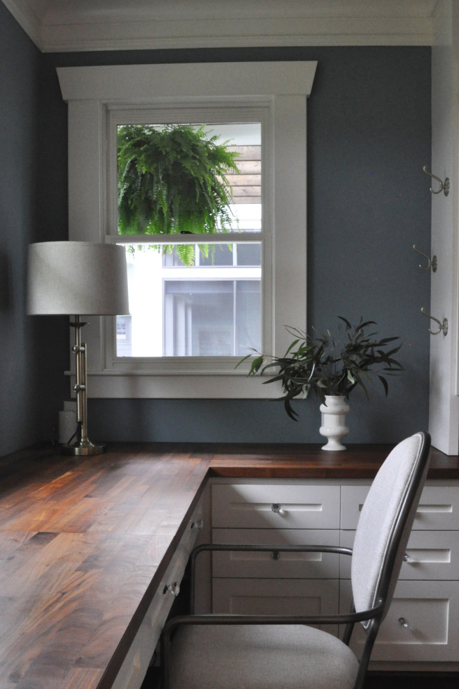 Imagen de despacho de estilo de casa de campo de tamaño medio sin chimenea con paredes azules, suelo de madera en tonos medios, escritorio empotrado y suelo marrón