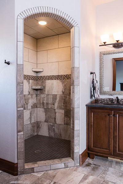 Example of a mid-sized mountain style master multicolored tile and porcelain tile porcelain tile and gray floor corner shower design with medium tone wood cabinets, white walls, an undermount sink, granite countertops and recessed-panel cabinets