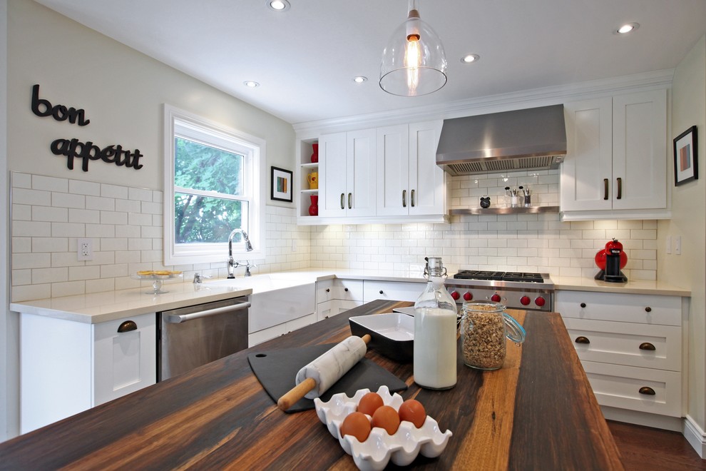 Design ideas for a small eclectic l-shaped kitchen in Toronto with a farmhouse sink, wood benchtops, white splashback, stainless steel appliances, medium hardwood floors and with island.