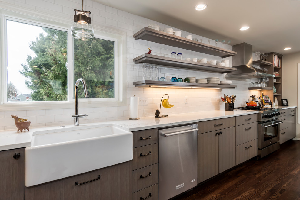 Mid-sized transitional l-shaped dark wood floor and brown floor open concept kitchen photo in Seattle with a farmhouse sink, flat-panel cabinets, gray cabinets, quartz countertops, white backsplash, subway tile backsplash, stainless steel appliances and an island