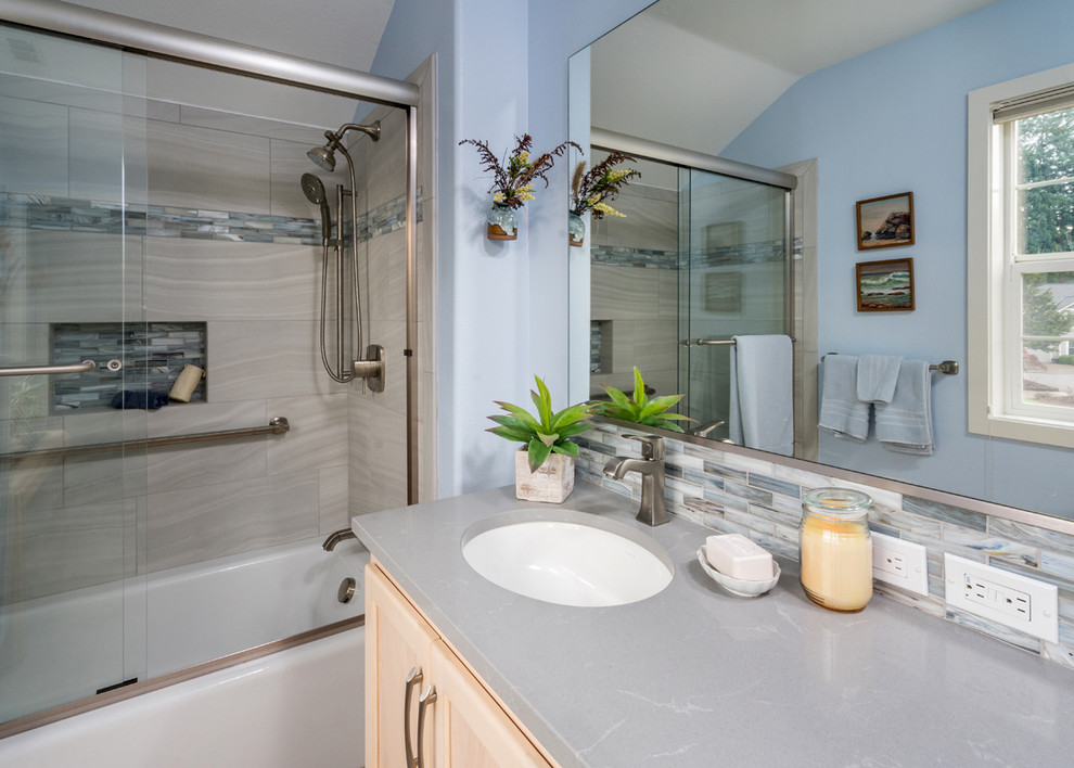 Design ideas for a mid-sized beach style 3/4 bathroom in Portland with shaker cabinets, light wood cabinets, an alcove tub, a shower/bathtub combo, beige tile, porcelain tile, blue walls, an undermount sink, engineered quartz benchtops, a sliding shower screen and grey benchtops.