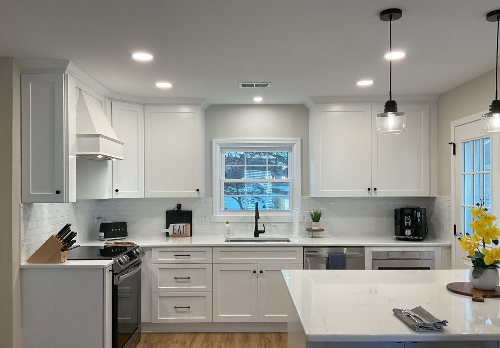 Design ideas for a small transitional l-shaped eat-in kitchen in Detroit with an undermount sink, shaker cabinets, white cabinets, quartz benchtops, white splashback, ceramic splashback, stainless steel appliances, medium hardwood floors, with island, brown floor and white benchtop.