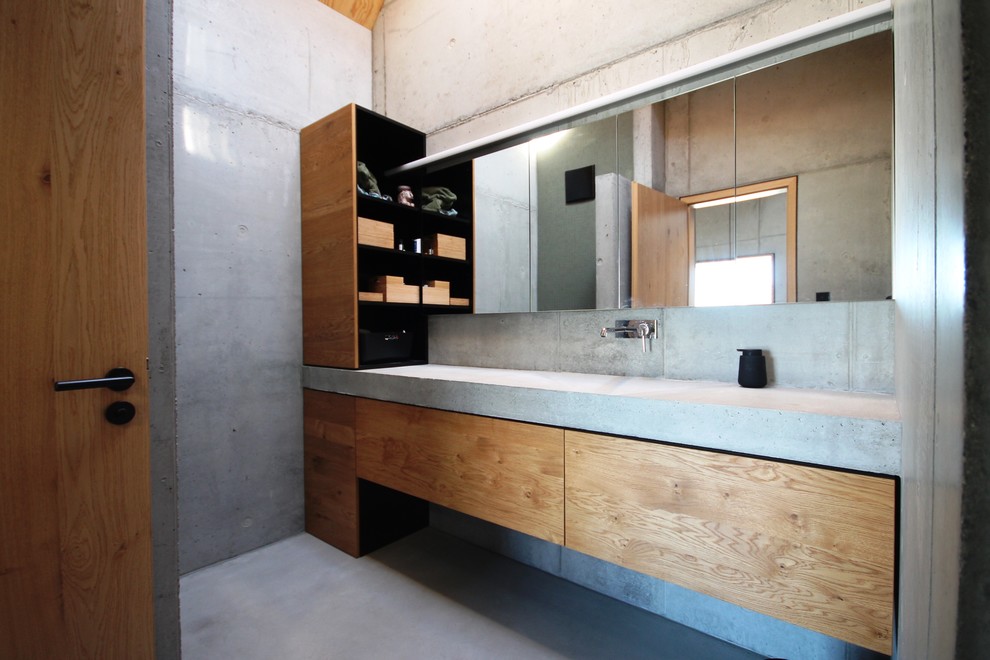 Design ideas for a mid-sized industrial 3/4 bathroom in Stuttgart with flat-panel cabinets, medium wood cabinets, a drop-in tub, a curbless shower, green tile, mosaic tile, grey walls, concrete floors, an integrated sink and concrete benchtops.
