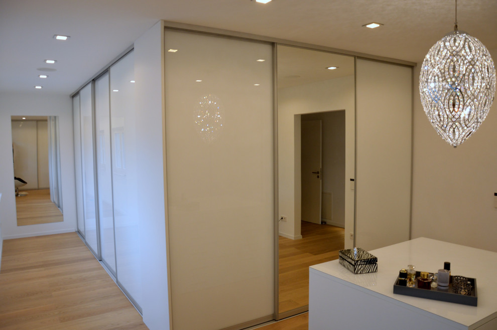 Großes Modernes Ankleidezimmer mit Ankleidebereich, flächenbündigen Schrankfronten, weißen Schränken, hellem Holzboden und beigem Boden in Nürnberg