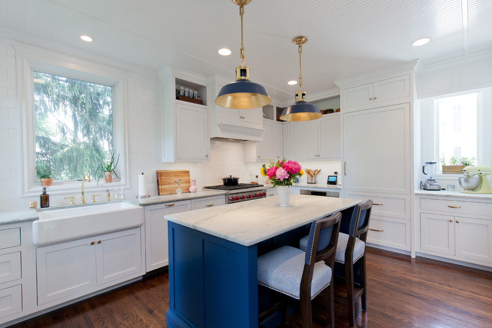 Mid-sized country l-shaped eat-in kitchen in Chicago with a farmhouse sink, shaker cabinets, blue cabinets, quartzite benchtops, white splashback, subway tile splashback, stainless steel appliances, dark hardwood floors, with island, brown floor and white benchtop.