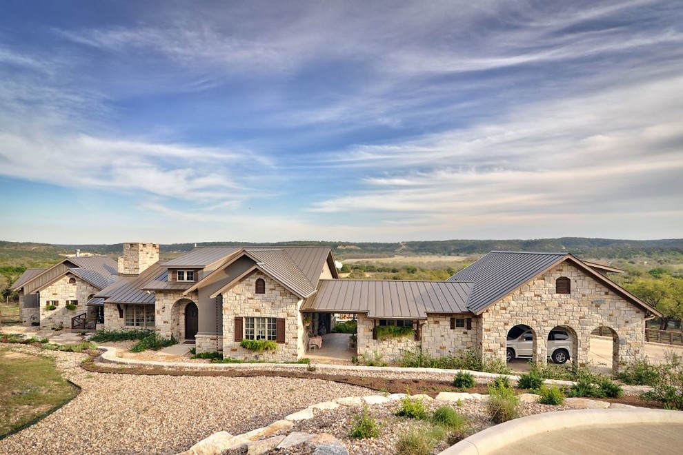 Design ideas for a large country one-storey exterior in Austin with stone veneer and a metal roof.