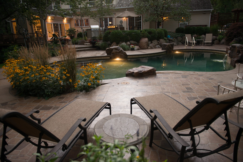 Small traditional backyard custom-shaped pool in Cedar Rapids with a hot tub and stamped concrete.