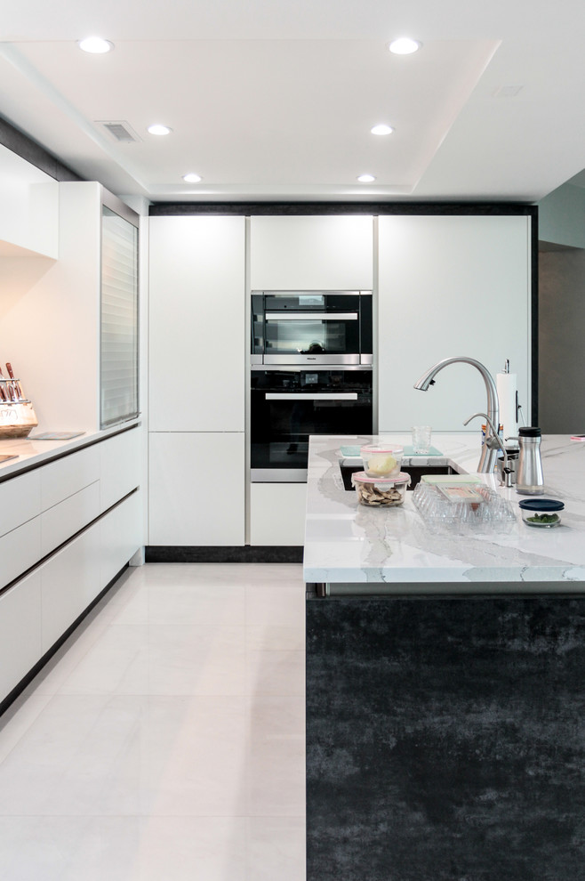 Mid-sized contemporary l-shaped open plan kitchen in Miami with an undermount sink, flat-panel cabinets, white cabinets, quartz benchtops, yellow splashback, stone slab splashback, stainless steel appliances, marble floors and with island.