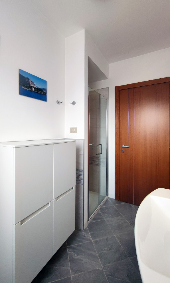 Photo of a mid-sized modern 3/4 bathroom in Turin with flat-panel cabinets, white cabinets, an alcove shower, white tile, porcelain tile, white walls, ceramic floors, an integrated sink, turquoise floor, a hinged shower door, a niche, a single vanity, a floating vanity and recessed.