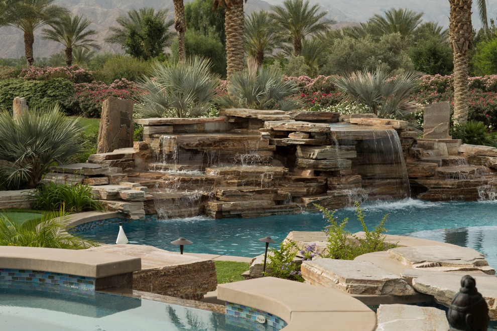 Example of a mid-sized transitional backyard concrete paver and round natural pool fountain design