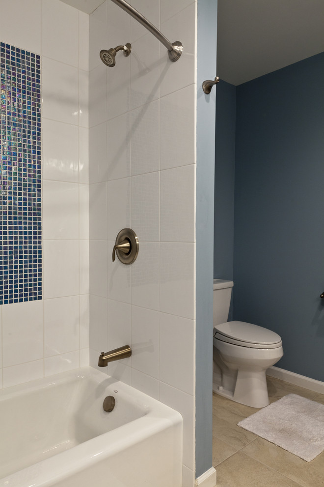 Mid-sized beach style bathroom in Bridgeport with an undermount sink, recessed-panel cabinets, white cabinets, engineered quartz benchtops, an alcove tub, a shower/bathtub combo, a two-piece toilet, beige tile, porcelain tile, blue walls and porcelain floors.