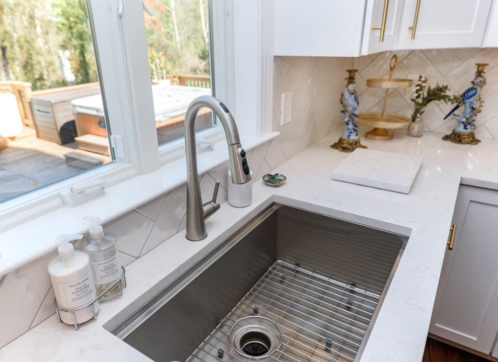 Inspiration for a mid-sized transitional galley brown floor and medium tone wood floor eat-in kitchen remodel in Baltimore with shaker cabinets, white cabinets, quartz countertops, white backsplash, subway tile backsplash, stainless steel appliances, an island, white countertops and an undermount sink