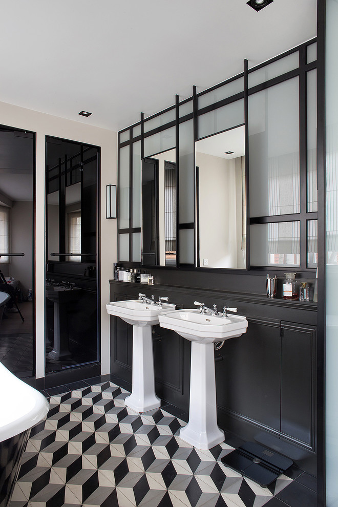 This is an example of a mid-sized contemporary bathroom in Paris with beaded inset cabinets, dark wood cabinets, a claw-foot tub, an alcove shower, a one-piece toilet, black and white tile, cement tile, grey walls, ceramic floors and a pedestal sink.