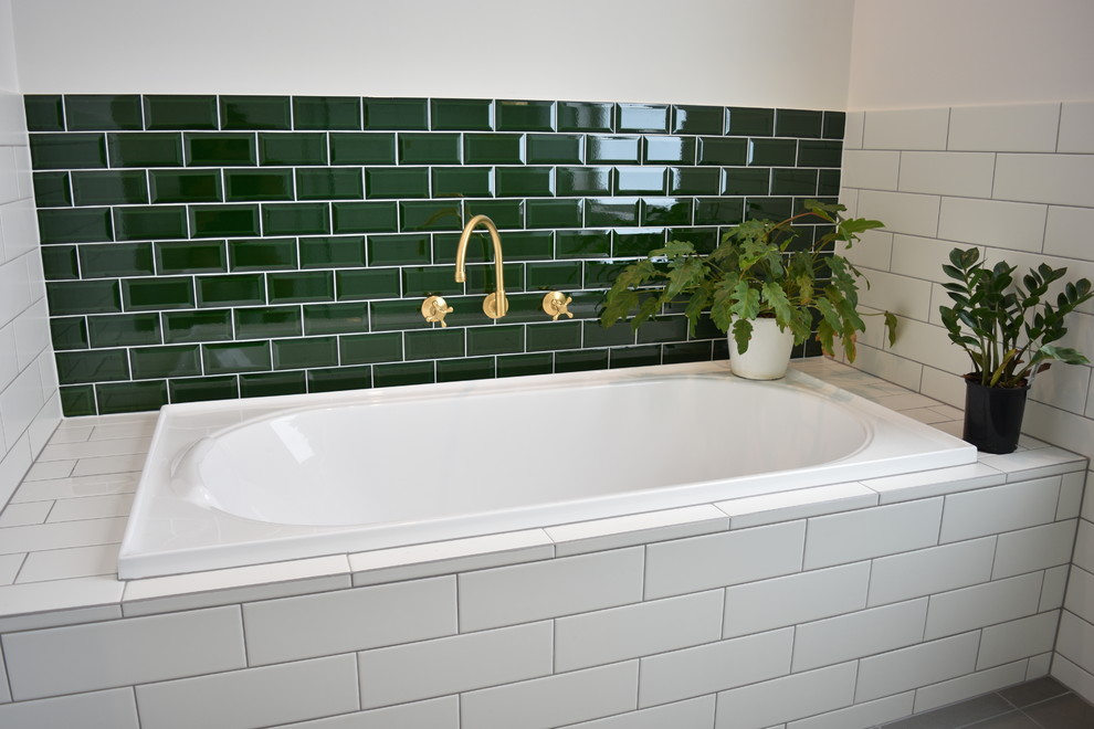 Photo of a mid-sized traditional bathroom in Adelaide with recessed-panel cabinets, white cabinets, a drop-in tub, a corner shower, a two-piece toilet, white tile, ceramic tile, white walls, ceramic floors, a drop-in sink, engineered quartz benchtops, grey floor, a hinged shower door and grey benchtops.